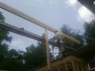 Carpenter setting a ridge beam over a new addition frame — Ice Dam Removal by Roofing Brothers in Newell