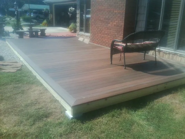 New wood deck and wicker chair beside a brick house in Newell
