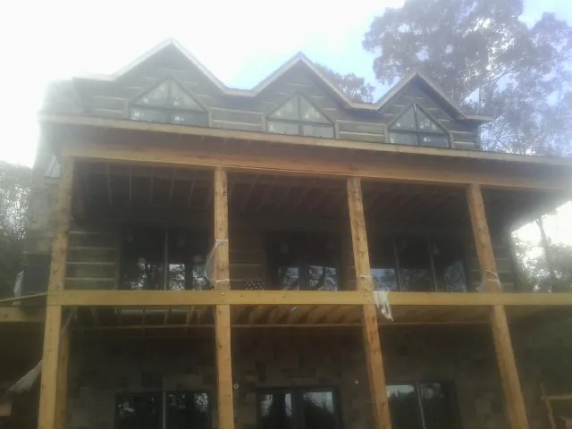 Dormers and porch framing on a large log home under construction — Roof Coating work by our crew in Newell
