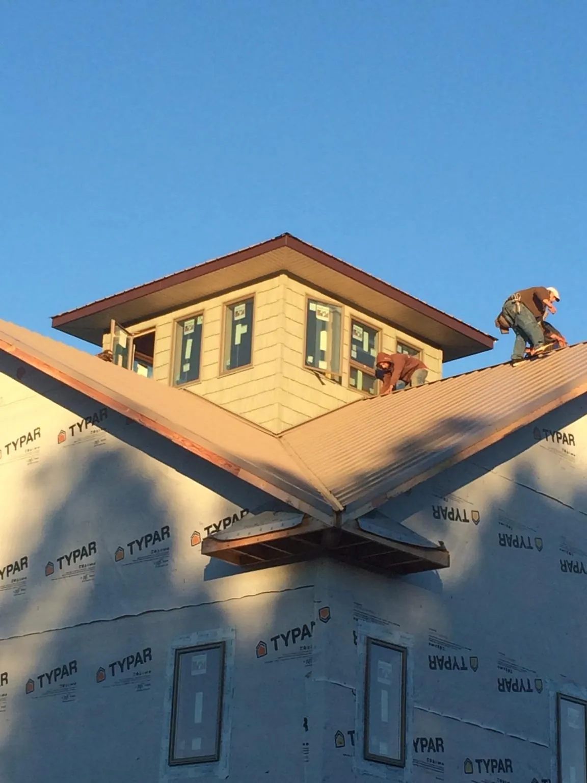 Roofers working around a rooftop cupola on a new metal roof at sunset — Roof Waterproofing in Newell by Roofing Brothers